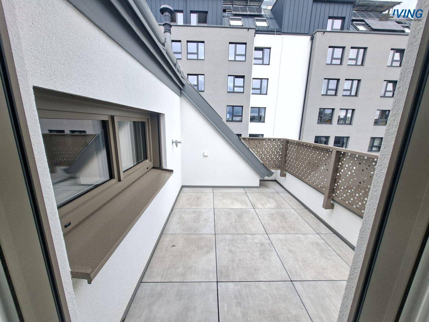 Kleiner Balkon mit Fliesenboden und Blick auf umliegende Gebäude.