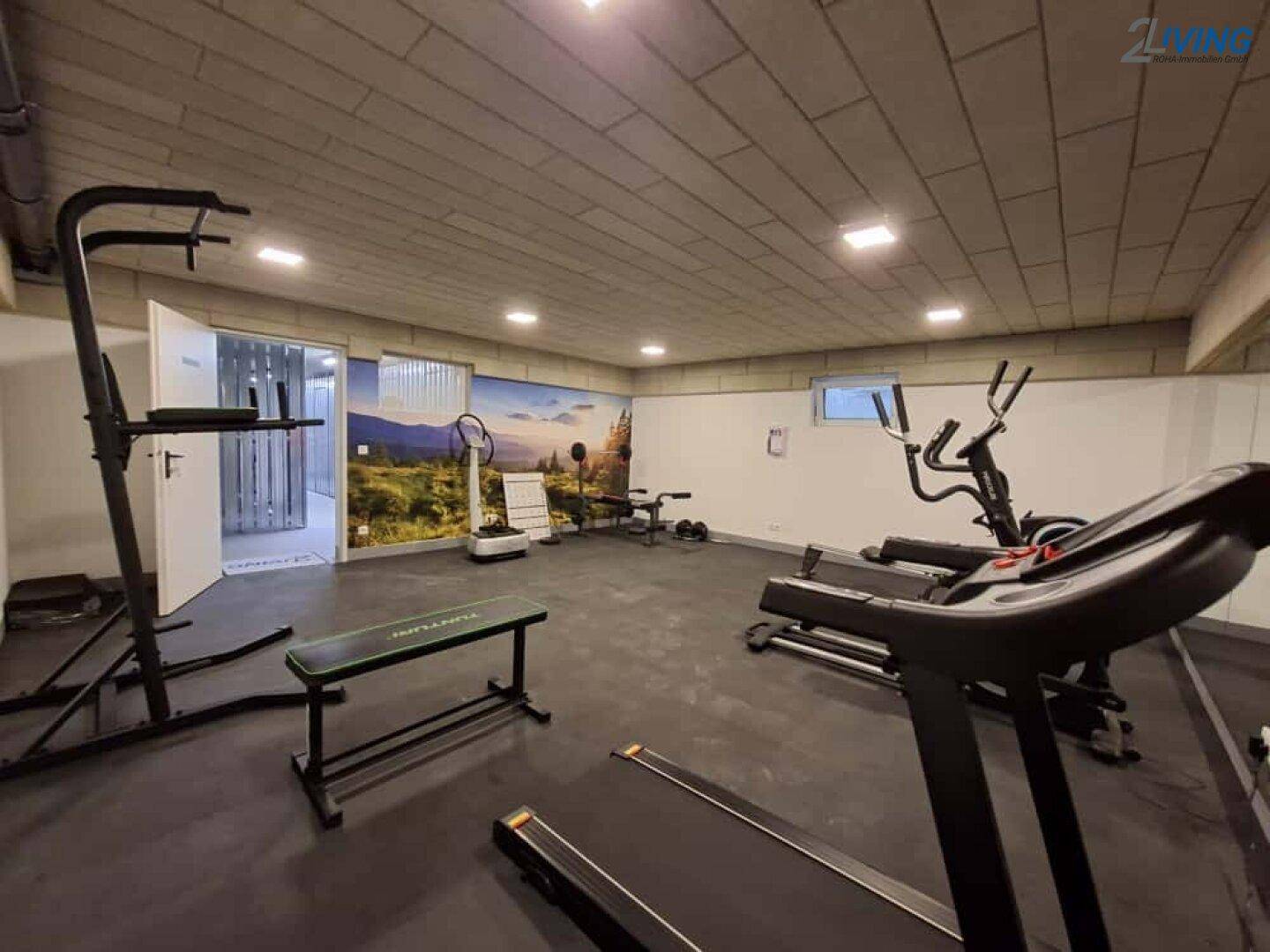 Gemeinschaftlicher Fitnessraum mit verschiedenen Trainingsgeräten und Gummiboden.