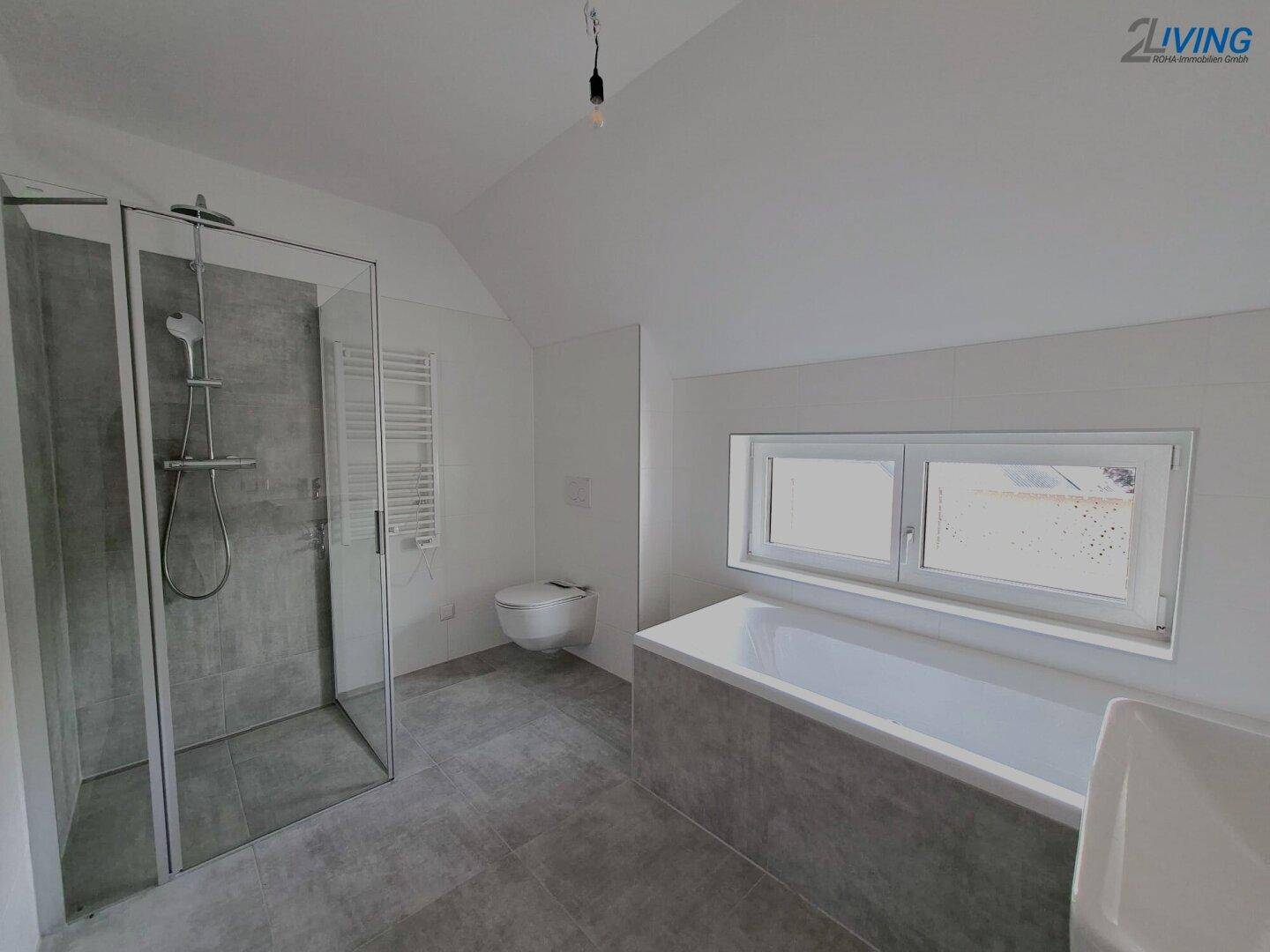 Modernes Badezimmer mit Badewanne, ebenerdiger Dusche, Wand-WC und Fenster für Tageslicht.