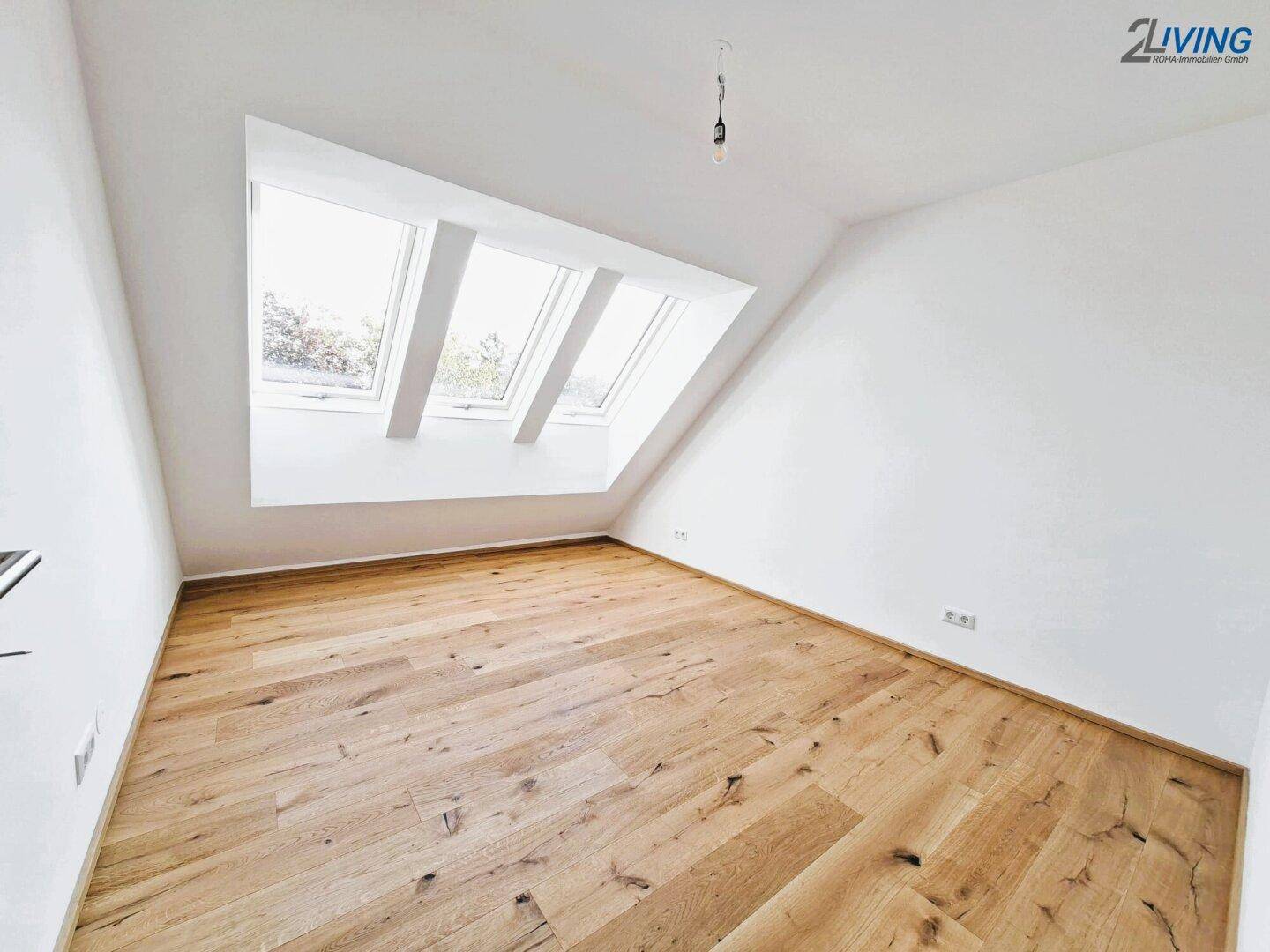 Leeres Zimmer im Dachgeschoss mit Holzboden und großen Dachfenstern, ideal für individuelle Gestaltung.