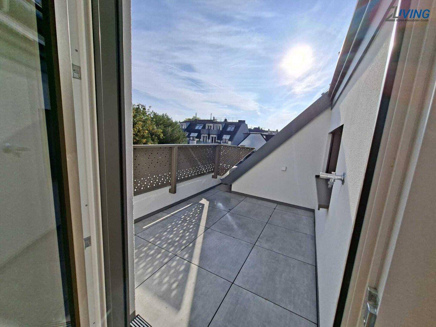 Sonniger Terrassenbereich mit moderner Brüstung und Blick auf die umliegenden Dächer.