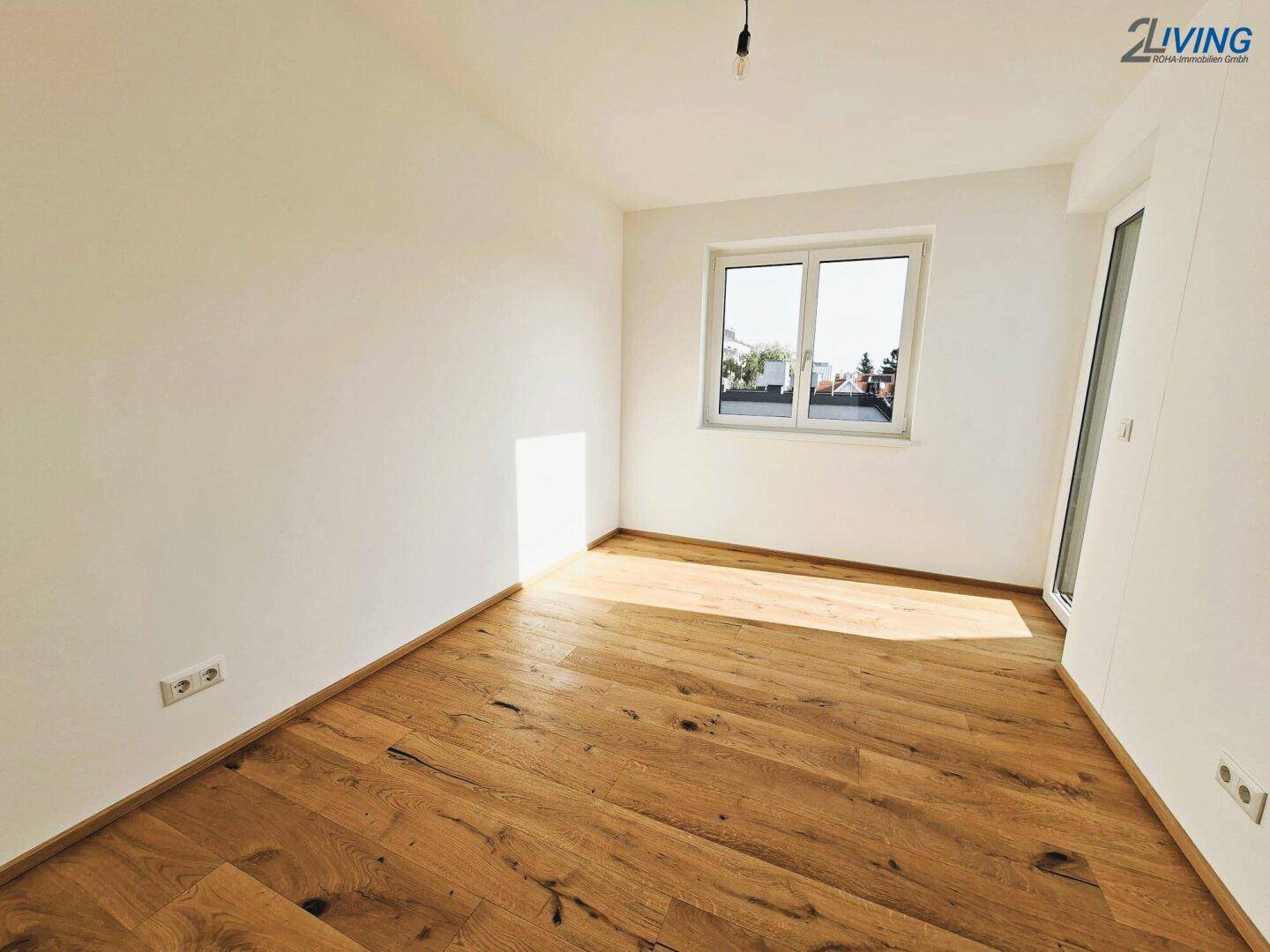 Heller Raum mit Holzboden und großem Fenster, bietet viel Tageslicht und eine angenehme Atmosphäre.
