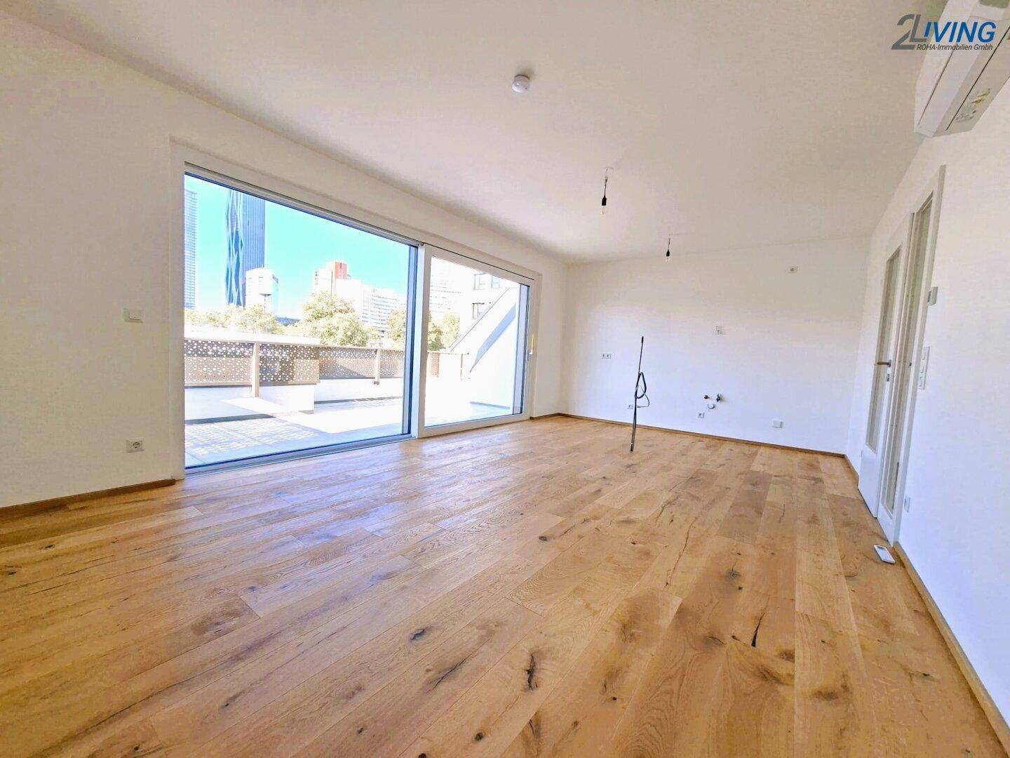 Geräumiger Wohnbereich mit Holzboden, großen Schiebetüren zur Terrasse und viel Tageslicht.