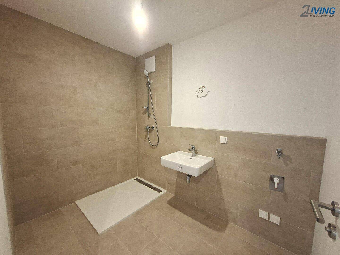 Modernes Badezimmer mit beigefarbenen Fliesen, ebenerdiger Dusche und schwebendem Waschbecken.