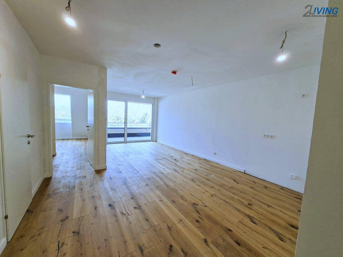 Heller, leerer Wohnraum mit hochwertigem Holzboden und großen Fenstern, bereit zur individuellen Gestaltung.