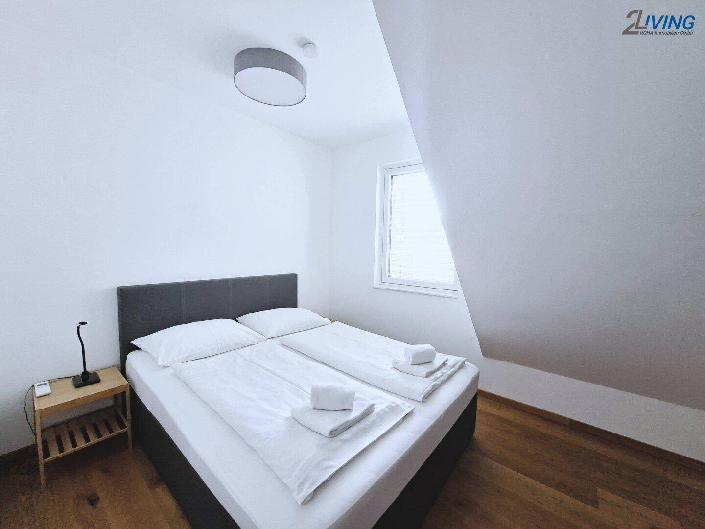 Gemütliches Schlafzimmer mit Doppelbett, Holzboden und Dachschräge, ideal für Gäste.