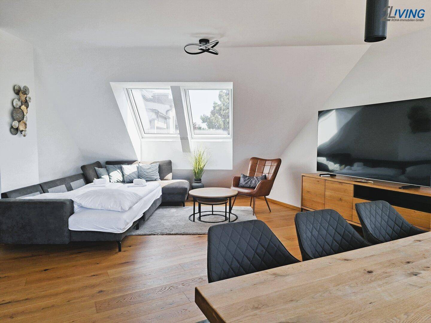Gemütlicher Wohnbereich mit Sofa, Sessel und Dachfenstern, ideal zum Entspannen.