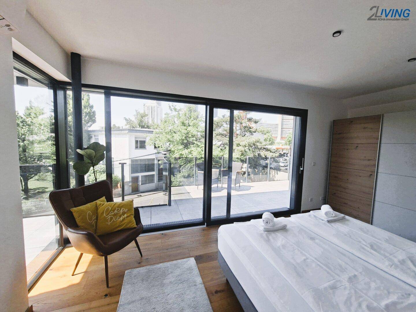 Schlafzimmer mit bodentiefen Fenstern, die viel Licht hereinlassen und einen Blick ins Grüne bieten.