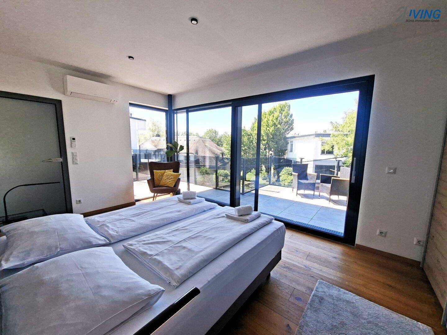 Modernes Schlafzimmer mit Doppelbett, Holzboden und Klimaanlage, mit Zugang zur Terrasse.