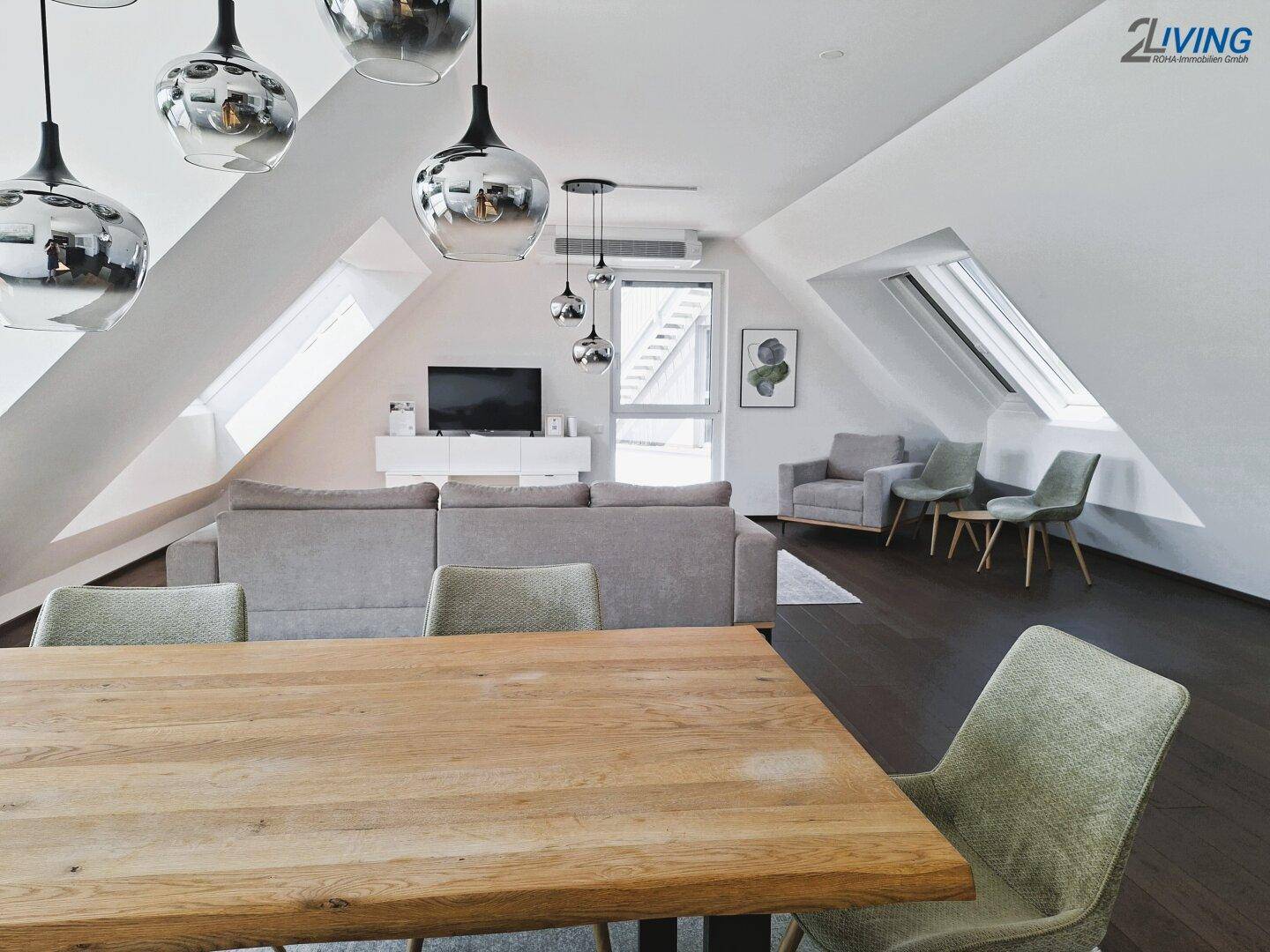 Geräumiger Wohn- und Essbereich mit Dachschrägen, Holzboden und modernen Deckenleuchten.