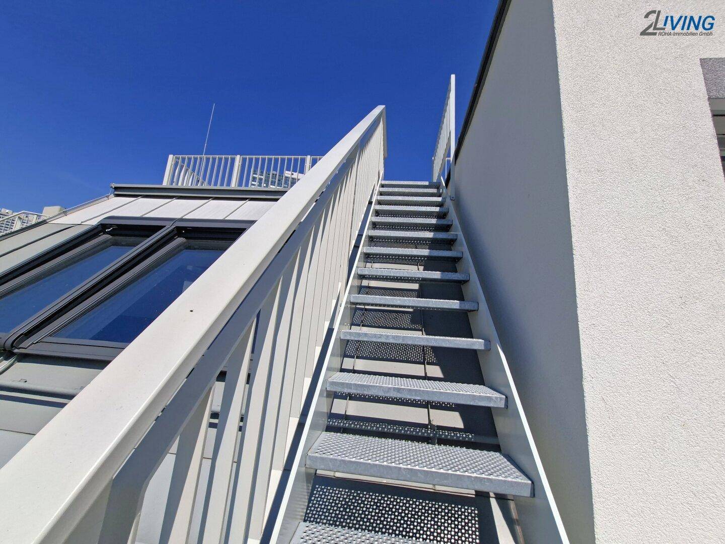 Metalltreppe führt zu einer oberen Dachterrasse mit Blick auf die Umgebung.