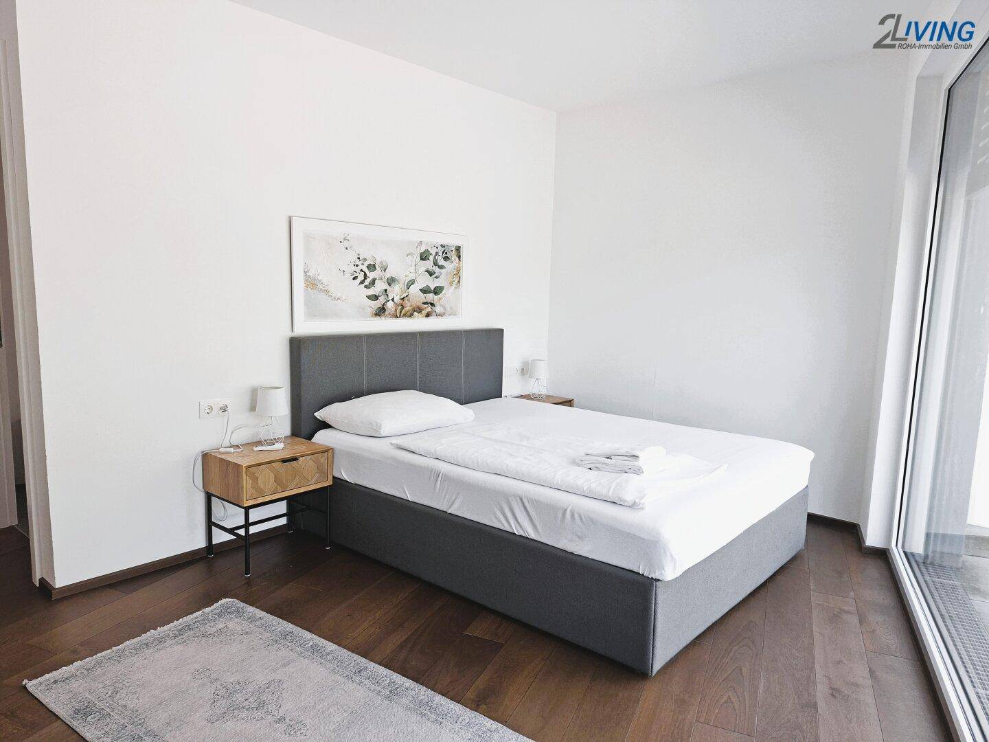 Geräumiges Schlafzimmer mit Doppelbett, dunklem Holzboden und Zugang zu einem Balkon.