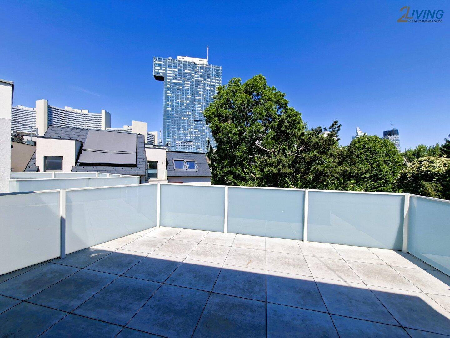 Sonnige Terrasse mit modernen Glasgeländern und weitem Blick auf die Stadt.