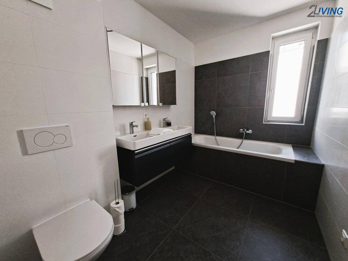 Modernes Badezimmer mit Badewanne, wandhängendem WC und großem Spiegelschrank.
