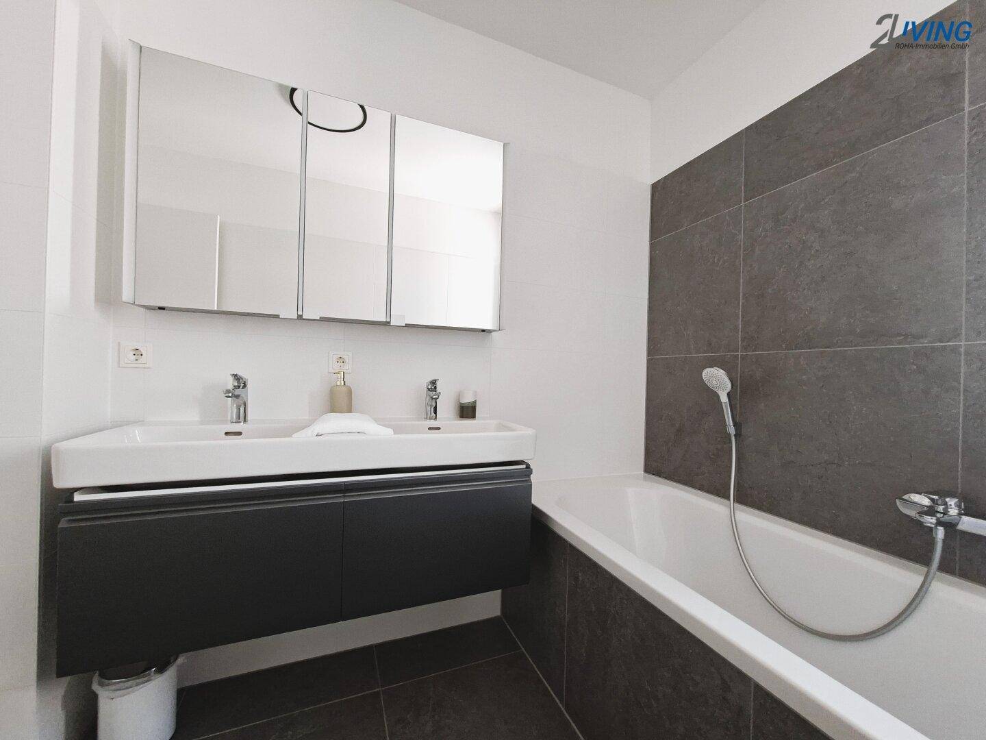 Helles Badezimmer mit Doppelwaschbecken, Badewanne und großem Spiegelschrank.