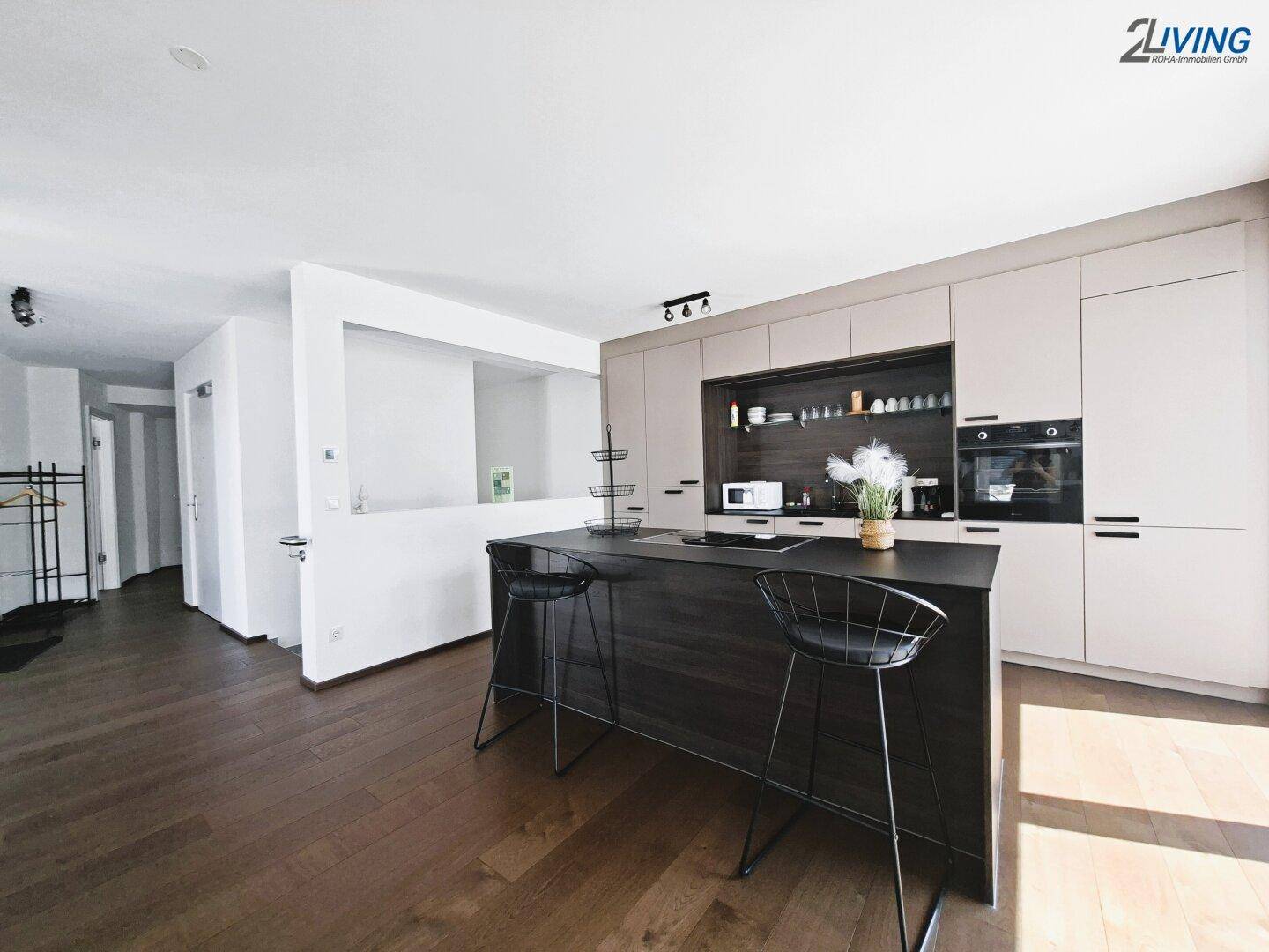 Moderne offene Küche mit Kücheninsel, integrierten Geräten und dunklem Holzboden.