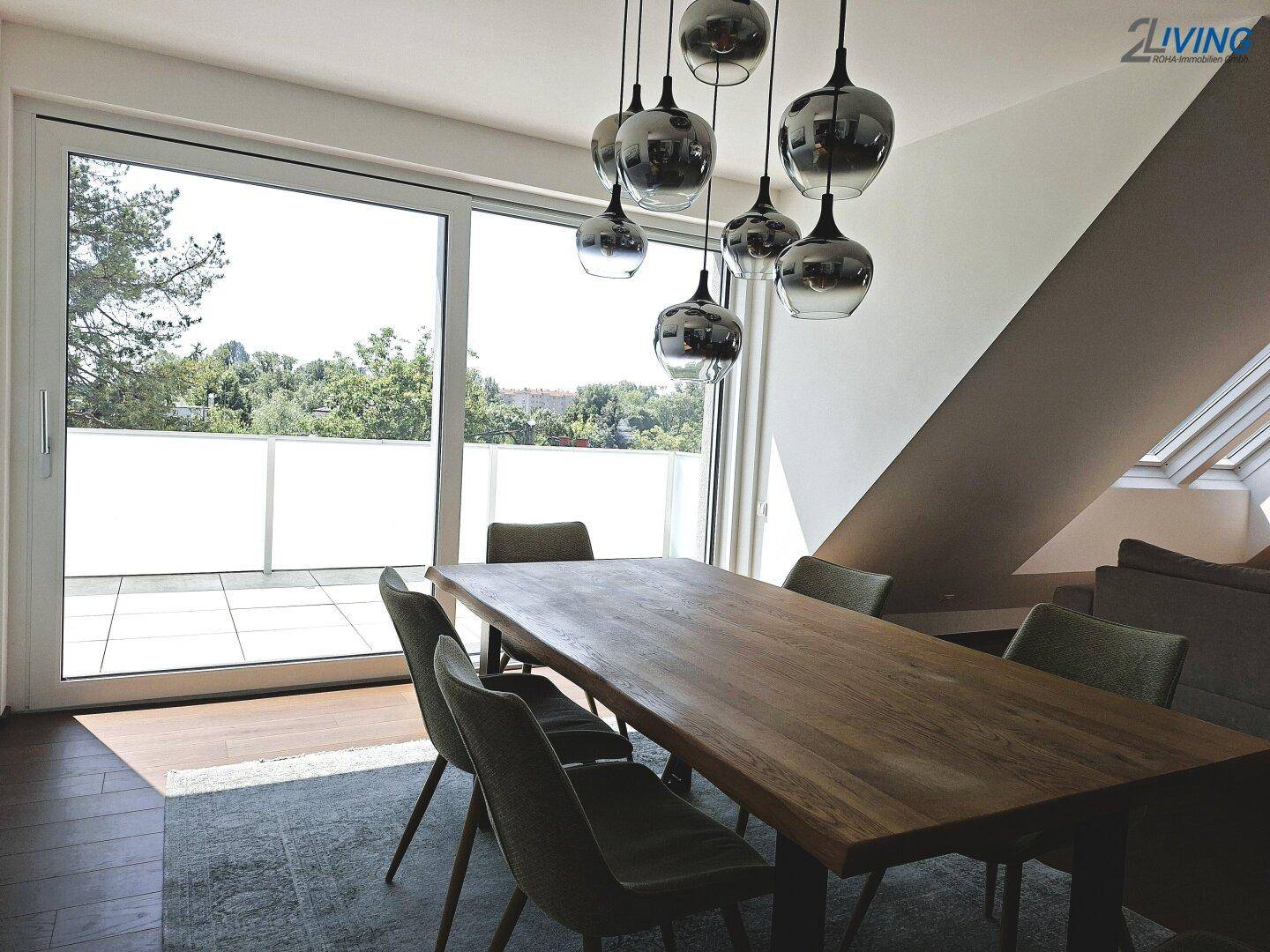 Heller Essbereich mit großem Holztisch, modernen Hängelampen und Zugang zur Terrasse.