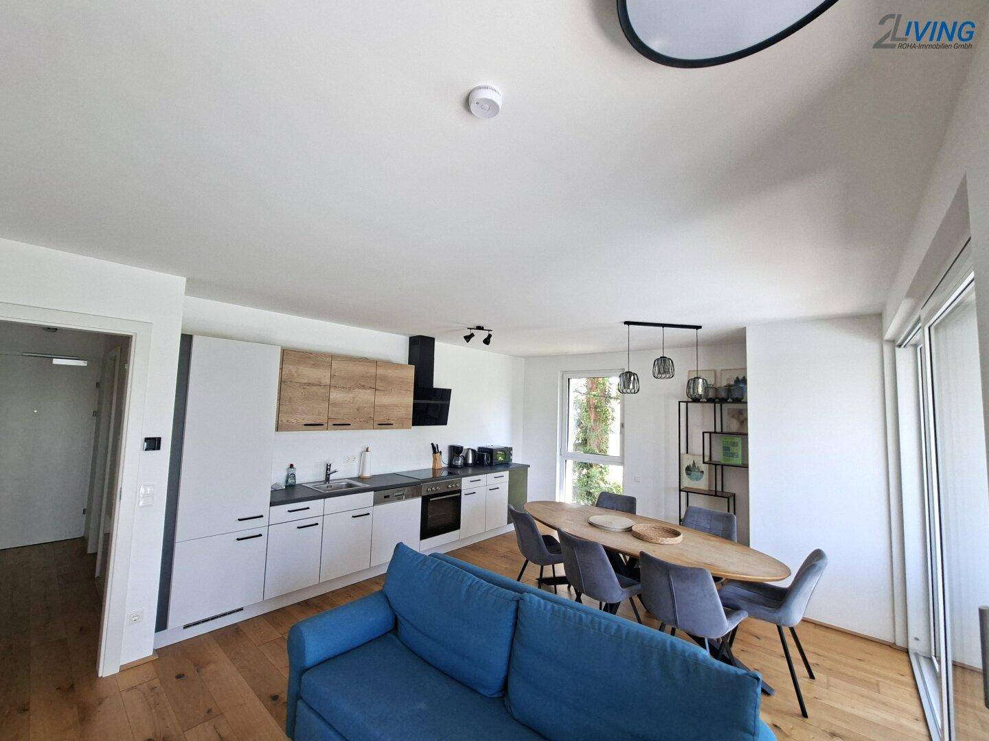 Heller Wohn-Essbereich mit integrierter Küche, Holzboden und modernem Design, ideal für offenes Wohnen.