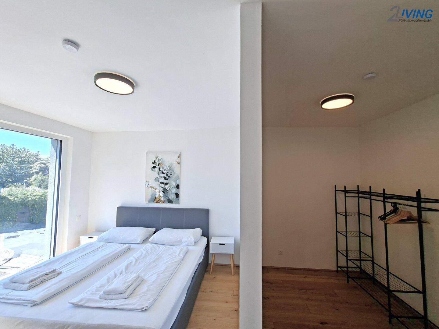 Schlafzimmer mit Doppelbett und offenem Kleiderschrankbereich, ausgestattet mit Holzboden.