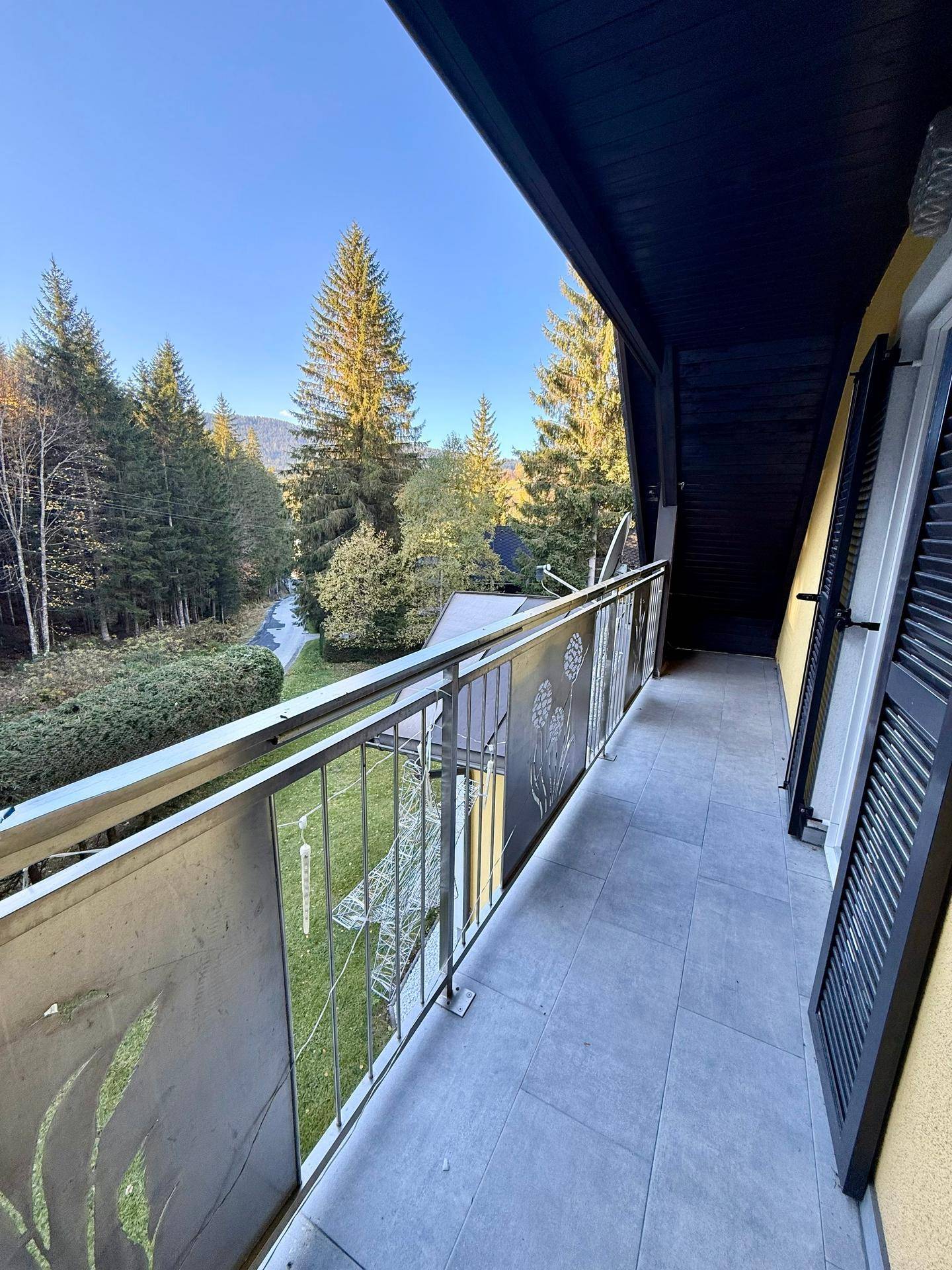 Balkon mit Metallgeländer und Blick auf die umliegende Waldlandschaft, ideal für frische Luft.