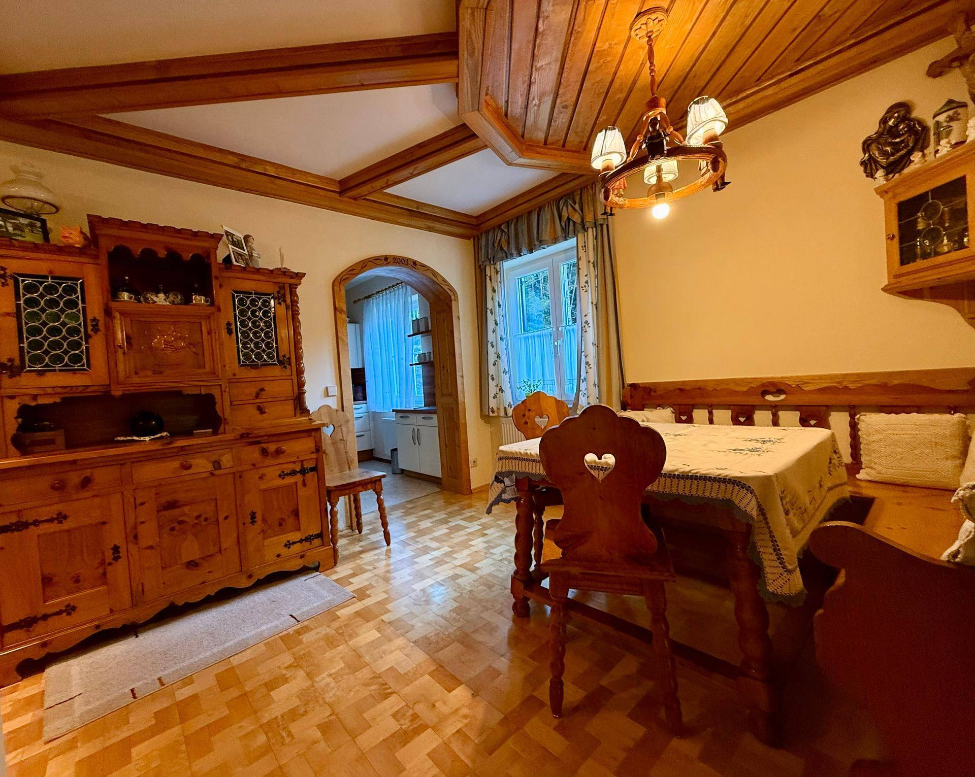 Rustikaler Essbereich mit Holztisch, Eckbank und traditionellen Holzmöbeln, angrenzend an die Küche.