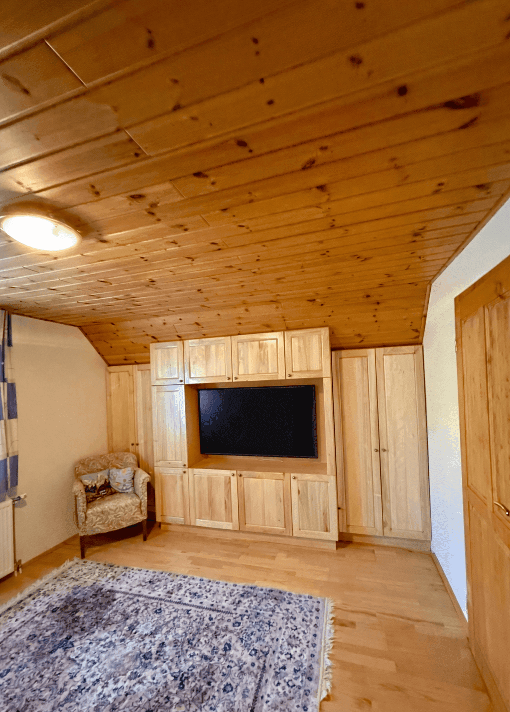 Helles Schlafzimmer mit Holzwänden, Einbauschränken und Teppich, bietet eine gemütliche Atmosphäre.