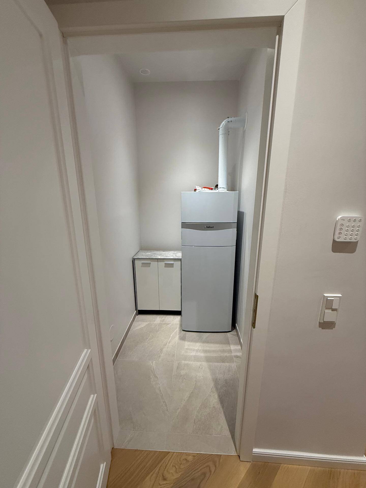 Kleiner Hauswirtschaftsraum mit Heizungsanlage und Stauraum, gefliestem Boden.