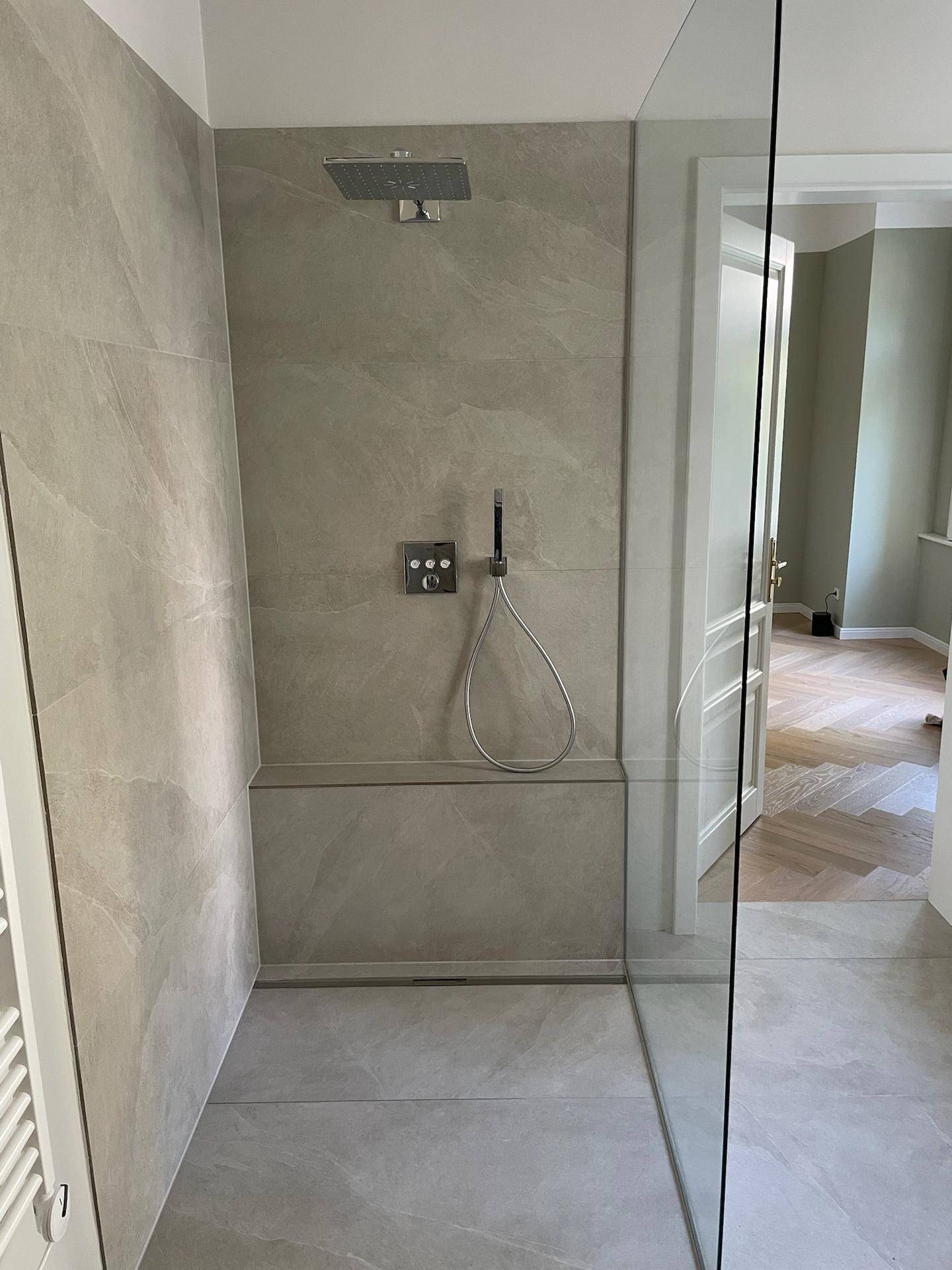 Moderne, begehbare Dusche mit Regenduschkopf und eleganten Fliesen.