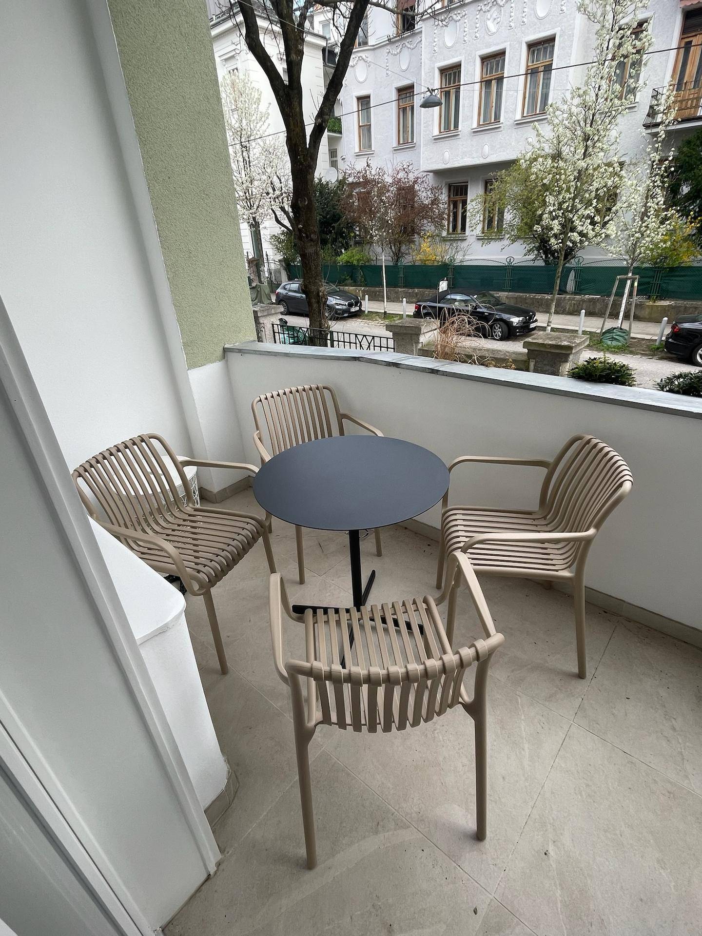 Kleiner Balkon mit modernem Tisch und Stühlen, ideal für Mahlzeiten im Freien.