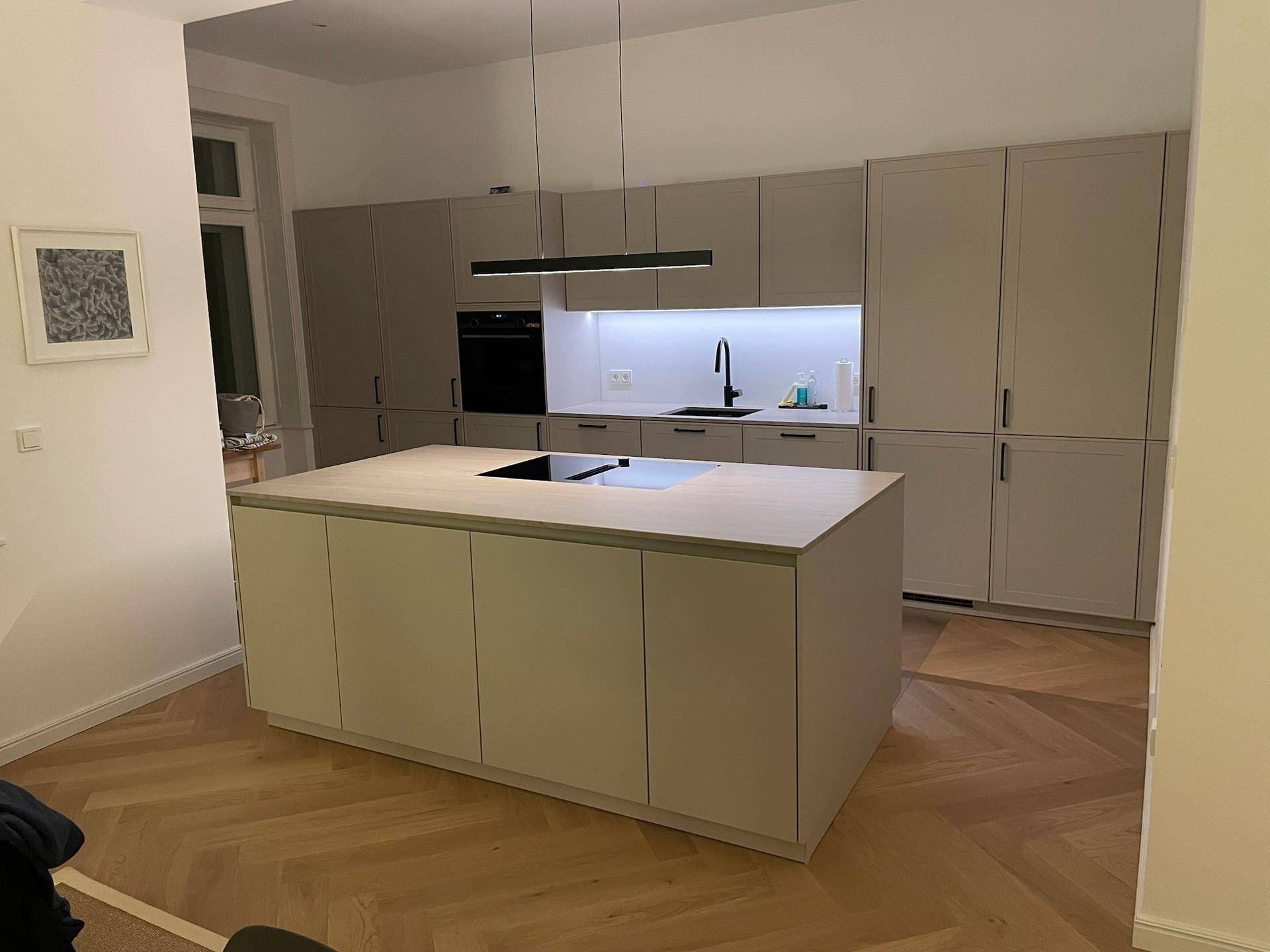 Moderne Einbauküche mit Kücheninsel, integrierten Geräten und viel Stauraum.