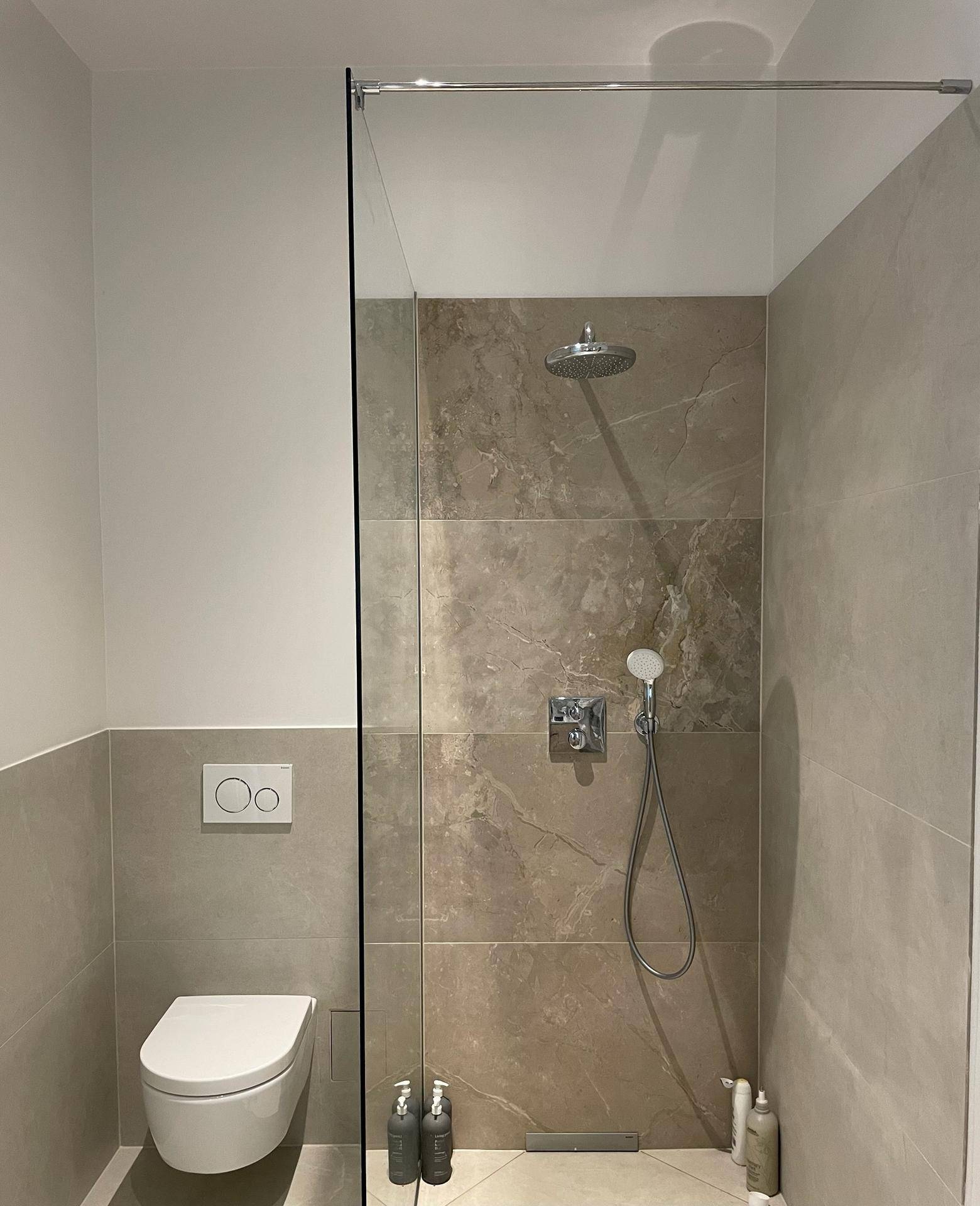 Begehbare Dusche mit Regenduschkopf und wandhängender Toilette in modernem Design.