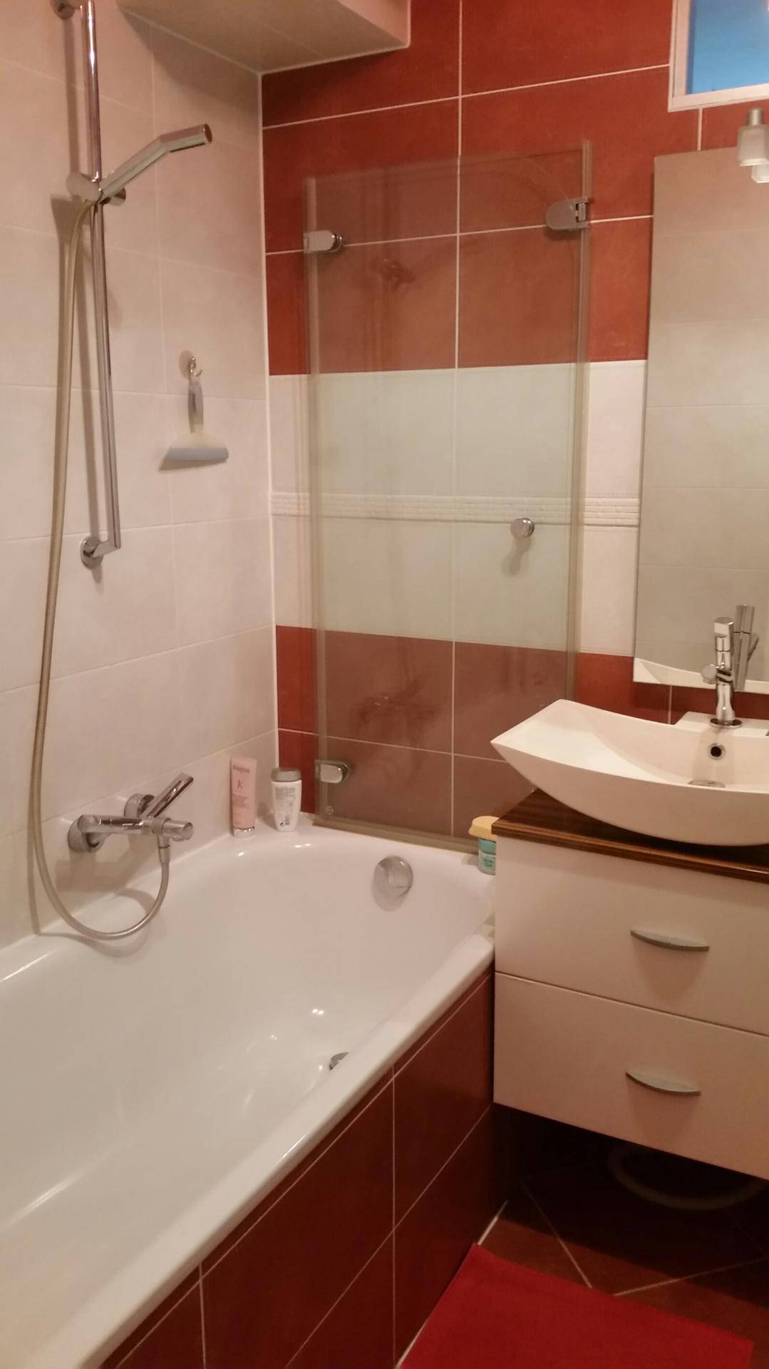 Badezimmer mit Badewanne, Duschvorrichtung und modernem Aufsatzwaschbecken.