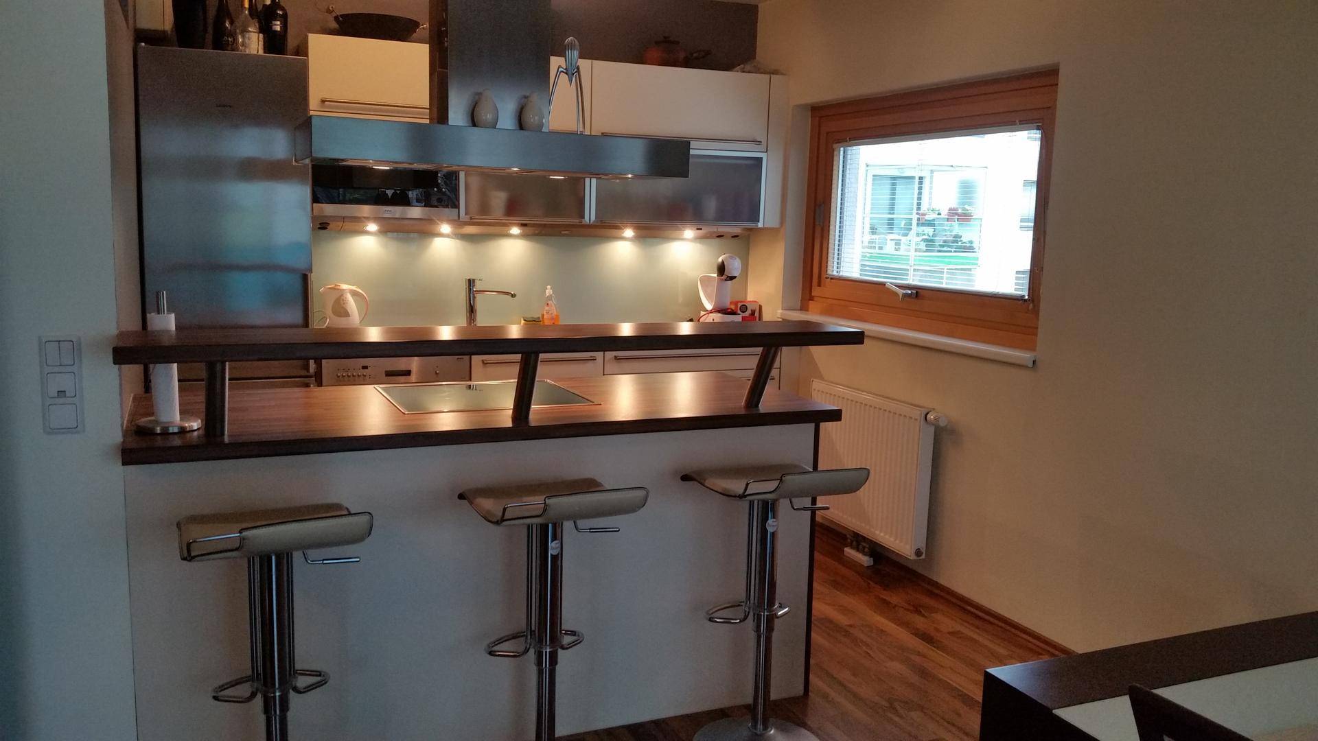 Moderne Küche mit Frühstücksbar, Barhockern und einem Fenster für natürliches Licht.