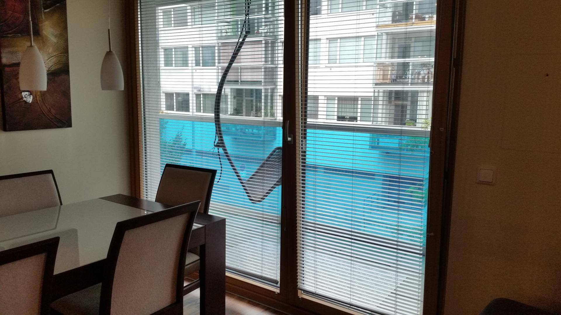 Großes Fenster mit Jalousien und Blick auf die umliegenden Wohngebäude.