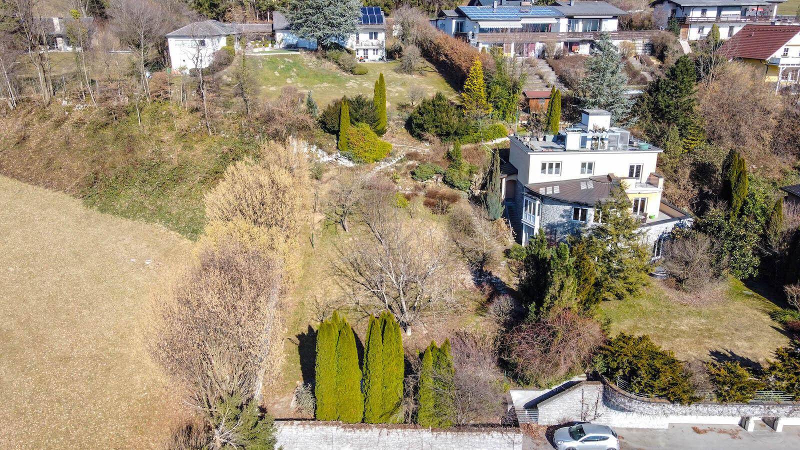 Luftaufnahme eines Anwesens am Hang mit großem Garten und umliegenden Häusern.