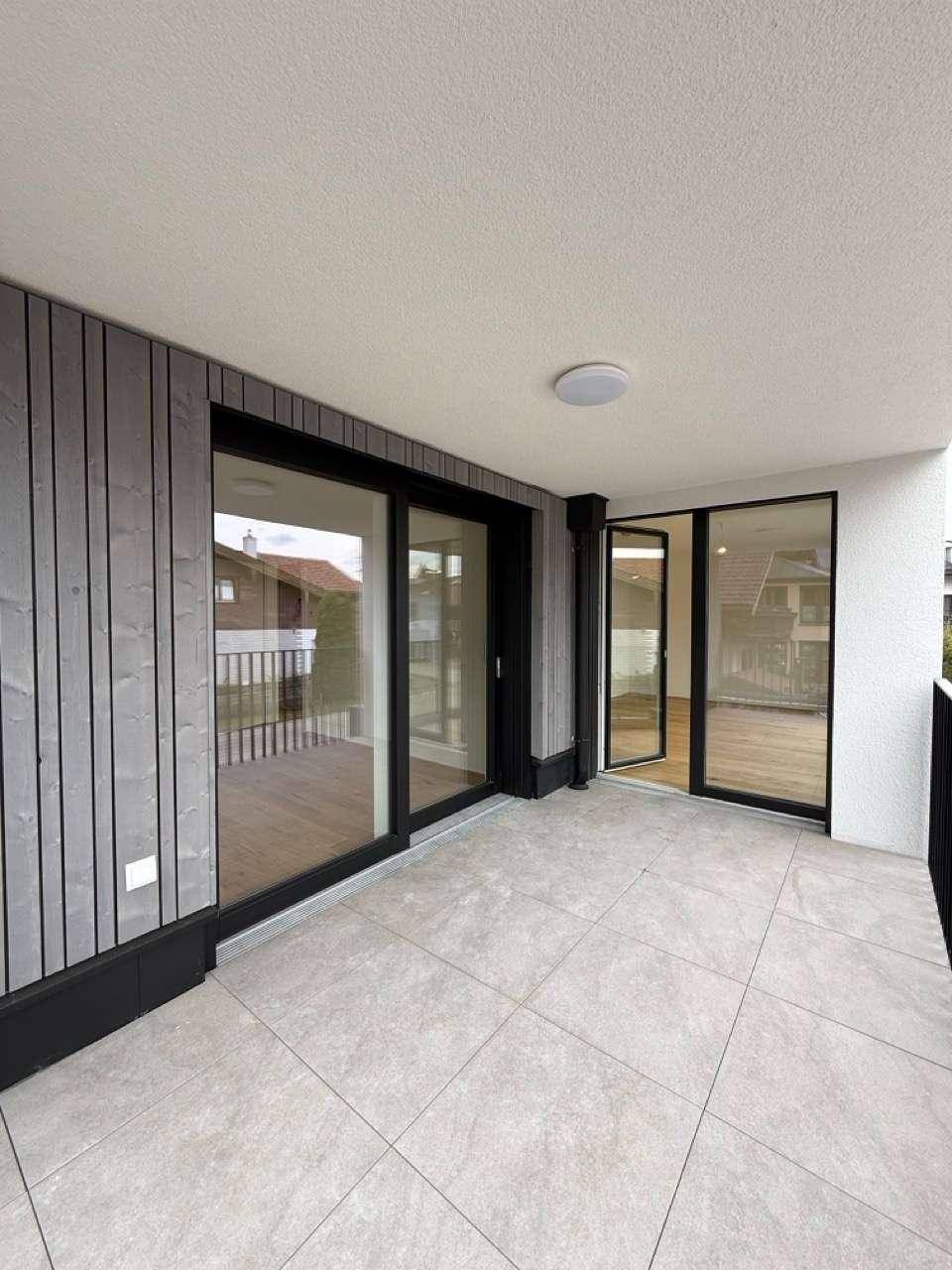 Moderner Balkon mit Fliesen und Holzfassade, der einen angenehmen Außenbereich schafft.