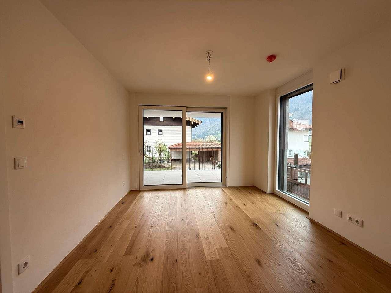 Moderner Wohnraum mit Eichenparkett und großen Fenstern, die viel natürliches Licht hereinlassen.