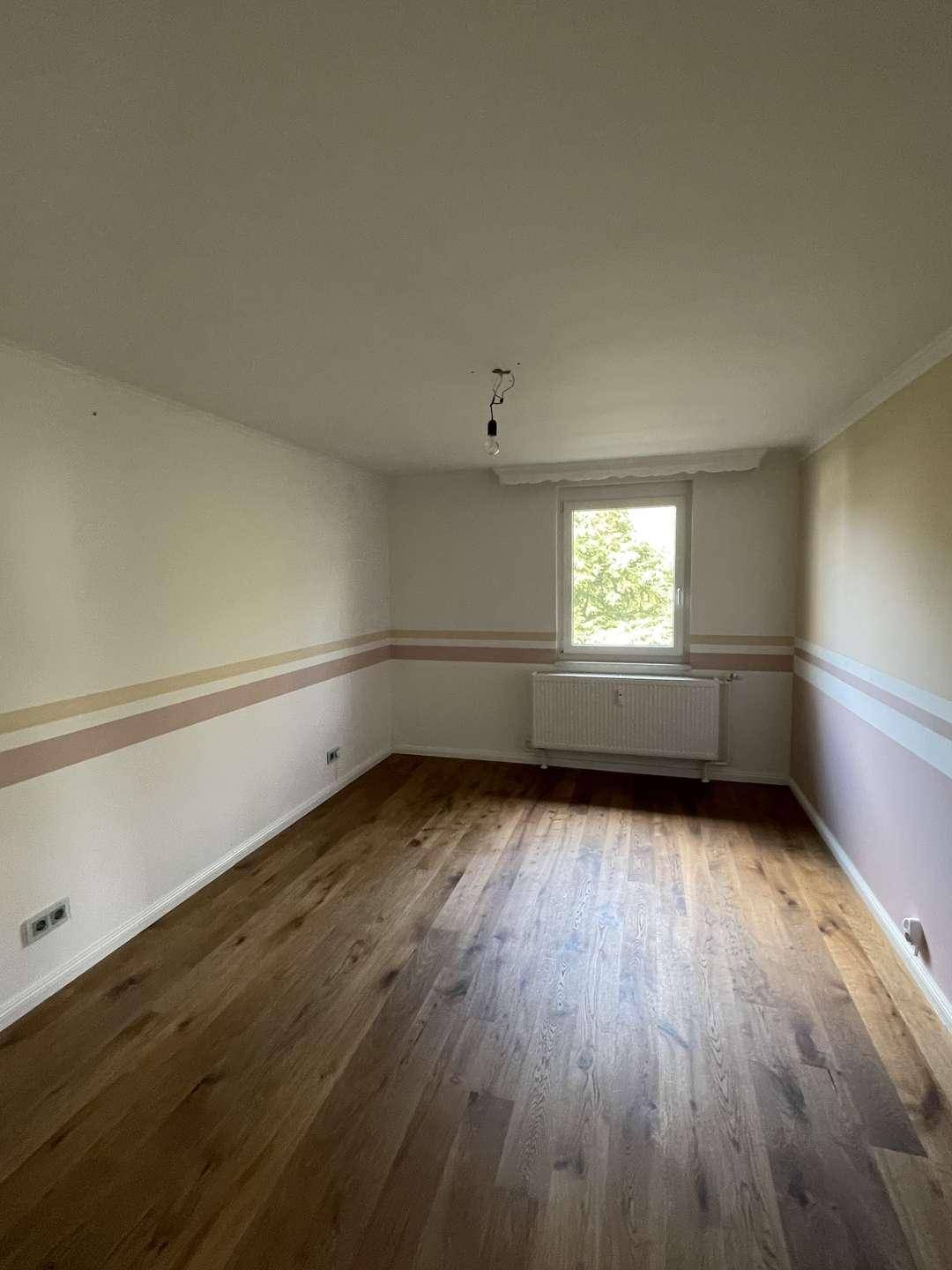 Schlafzimmer mit Holzboden und gestreiften Wänden, bietet eine gemütliche Atmosphäre und Tageslicht.