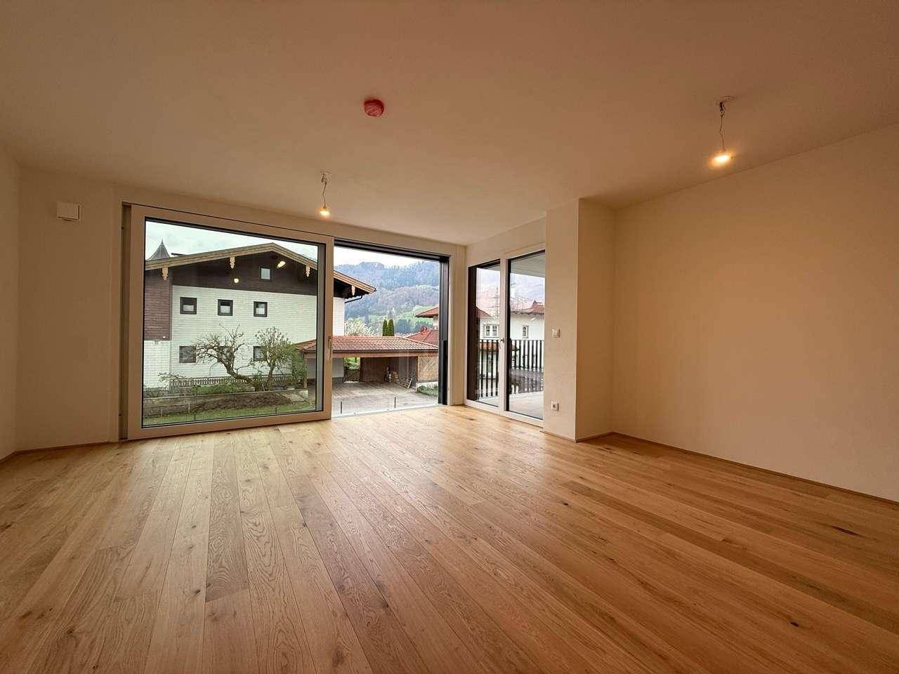 Heller Wohnraum mit Eichenparkett und großen Schiebetüren, die einen weiten Bergblick bieten.