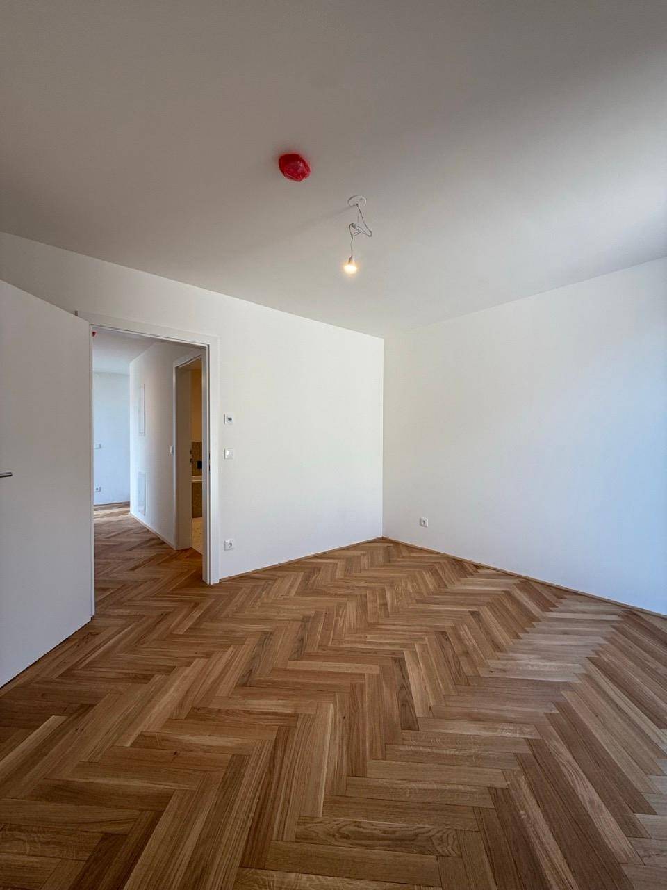 Helles Schlafzimmer mit elegantem Fischgrätparkett und frisch gestrichenen weißen Wänden.