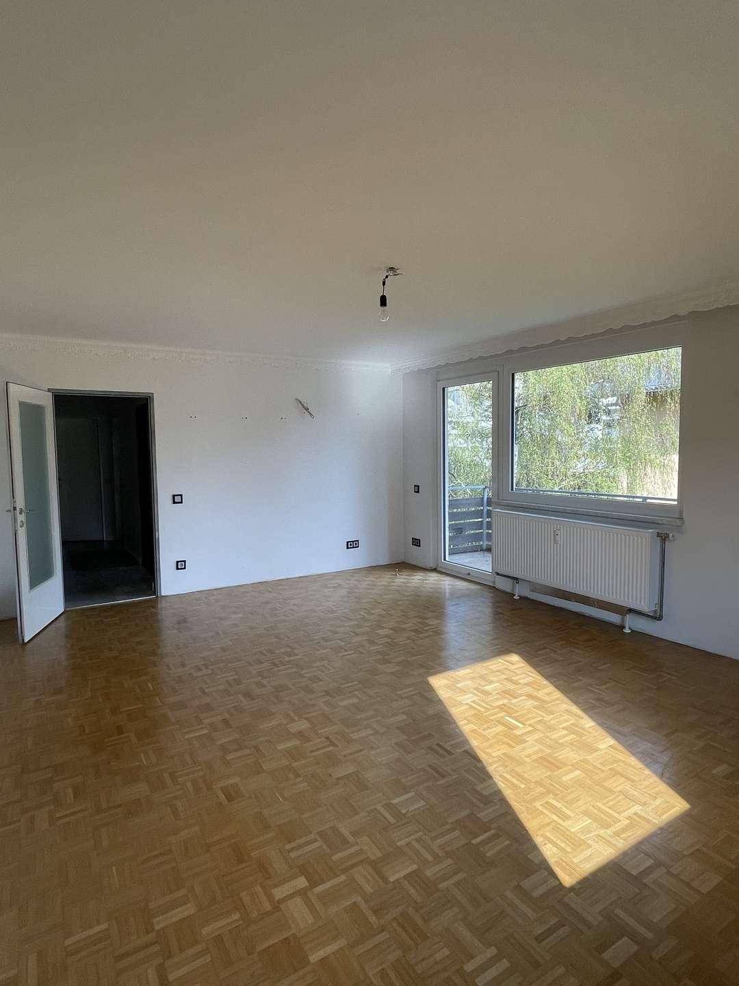 Geräumiges Wohnzimmer mit Parkettboden und viel Tageslicht, ideal für neue Einrichtungsideen.