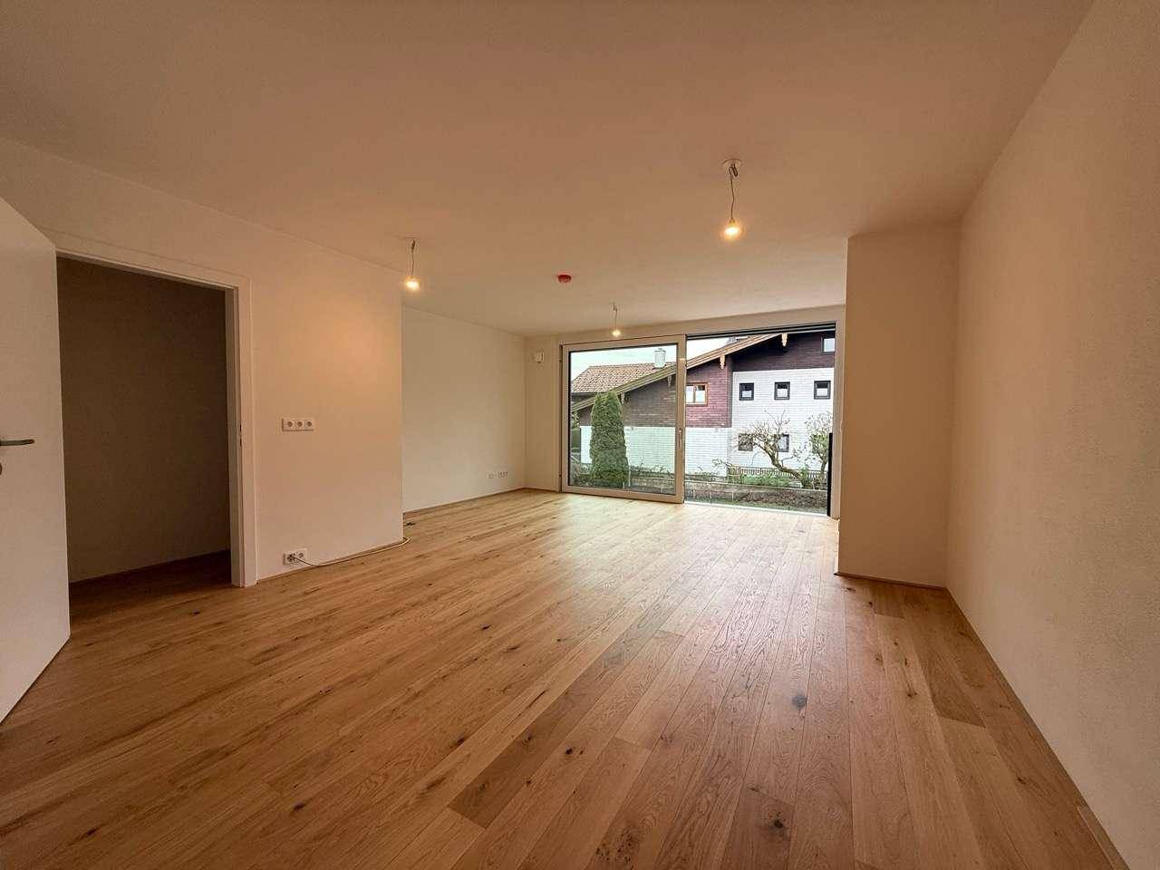 Geräumiger Wohnraum mit Parkettboden und viel Tageslicht durch die großen Fensterfronten.