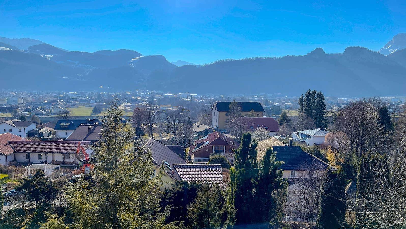 Weitblick über eine Siedlung mit verschiedenen Häusern und Bergen im Hintergrund.