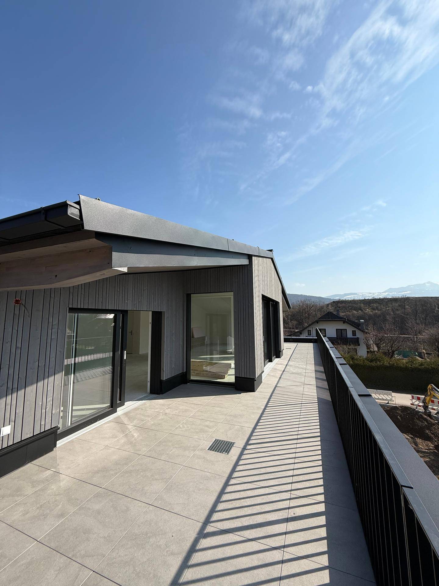Geräumige Dachterrasse mit Fliesenboden und weitem Blick auf die umliegende Berglandschaft.
