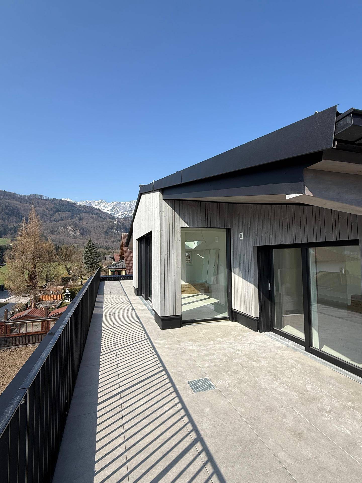 Helle Dachterrasse mit moderner Gestaltung und beeindruckendem Panoramablick auf die Berge.