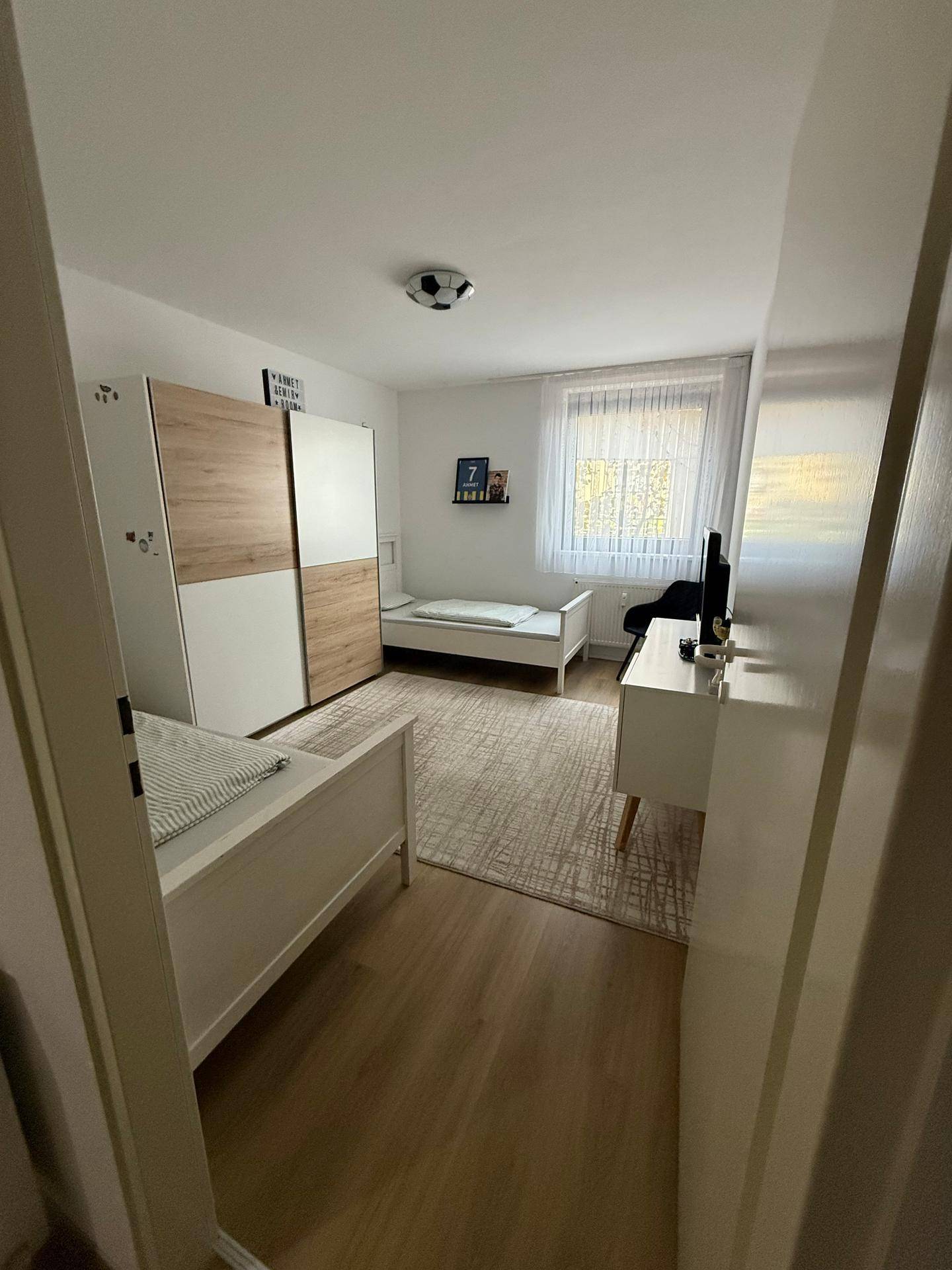 Kinderzimmer mit zwei Einzelbetten, Kleiderschrank und Holzboden.