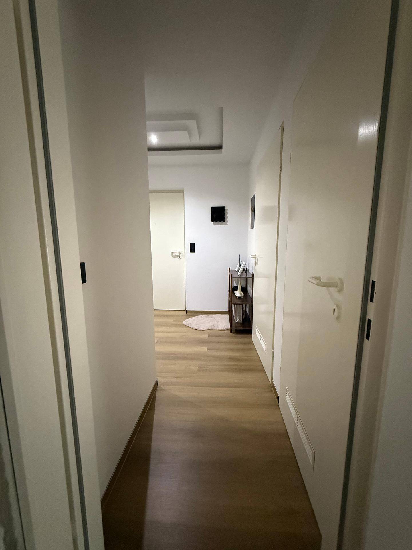 Langer Flur mit Holzboden und indirekter Deckenbeleuchtung.