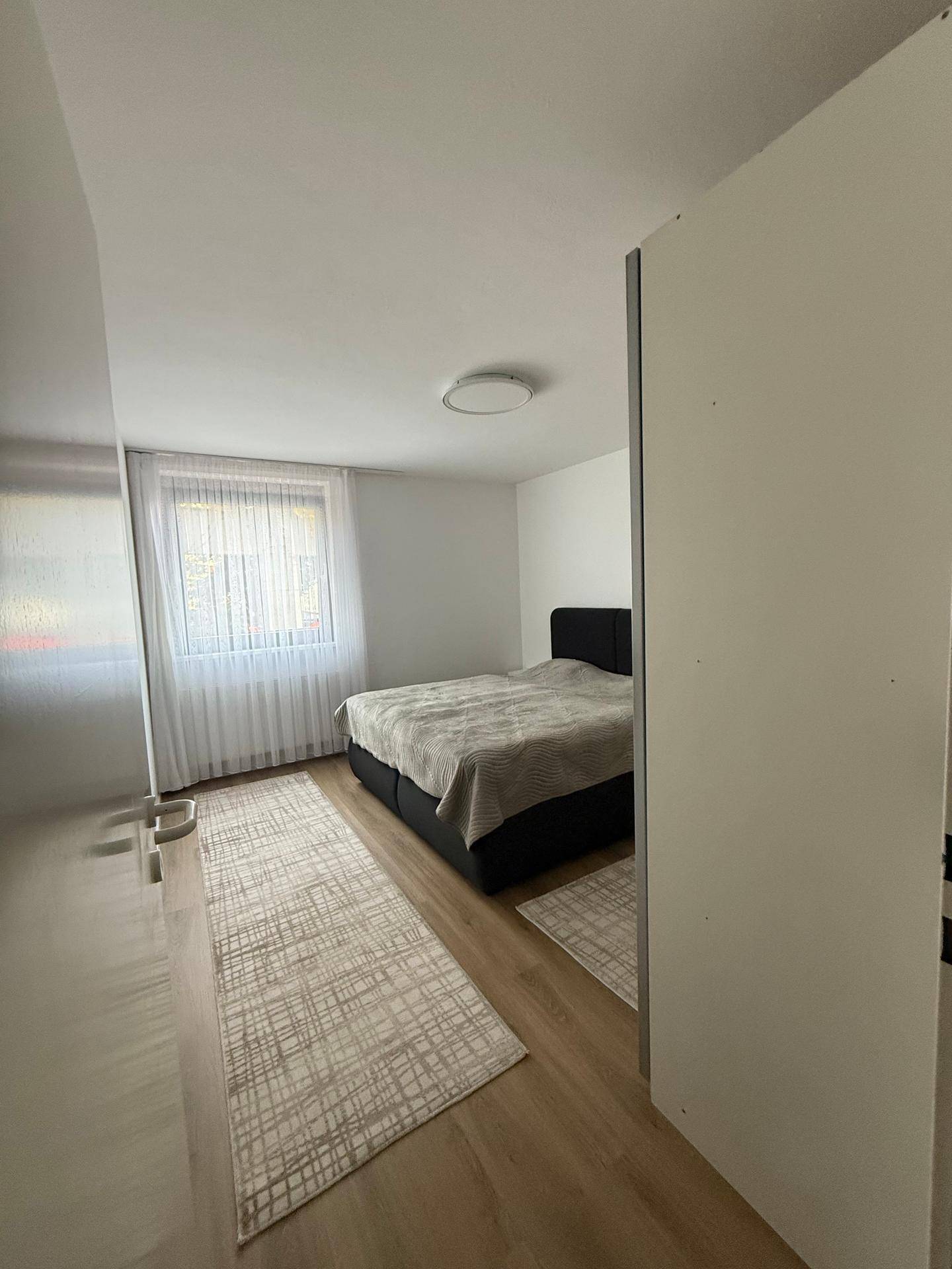 Schlafzimmer mit Doppelbett, Holzboden und großem Fenster für viel Tageslicht.
