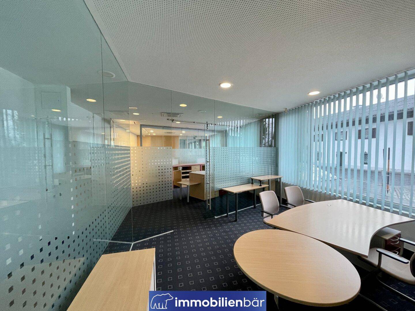 Moderner Bürobereich mit Teppichboden, Glaswänden und funktionalen Büromöbeln, ideal für Teamarbeit.
