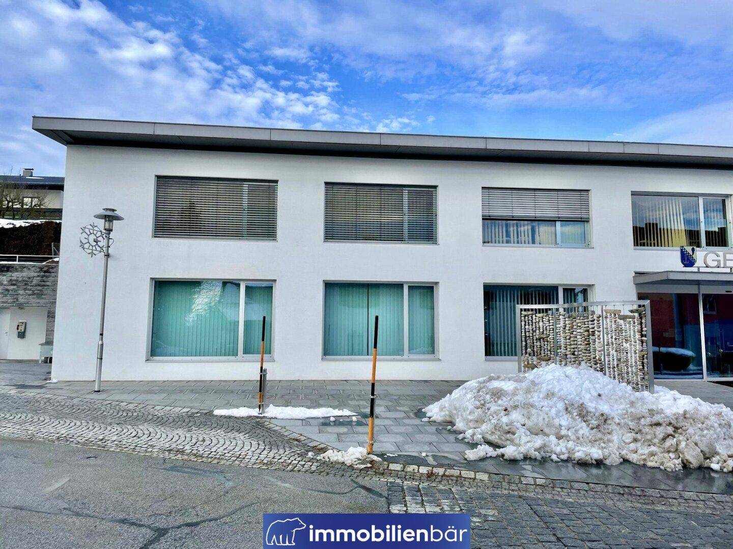 Außenansicht des modernen Gebäudes mit weißer Fassade und großen Fensterfronten, umgeben von winterlicher Landschaft.